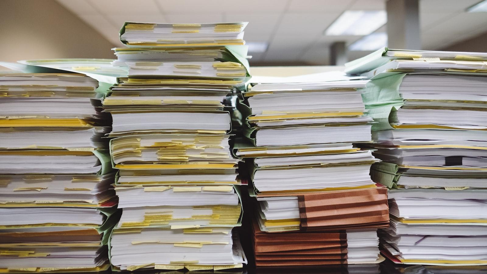 Tall stacks of paper files and folders on a desk